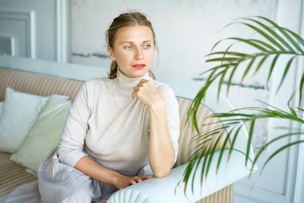 Retrato de una bella mujer sentada en un sofá en una habitación luminosa