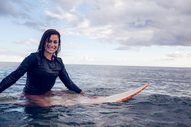 Retrato de una bella mujer con tabla de surf en el agua
