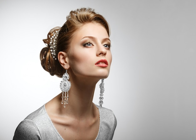 Retrato de una bella mujer con un vestido blanco y grandes aretes.