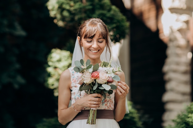 Retrato de una bella novia en velo con un ramo de flores en sus manos