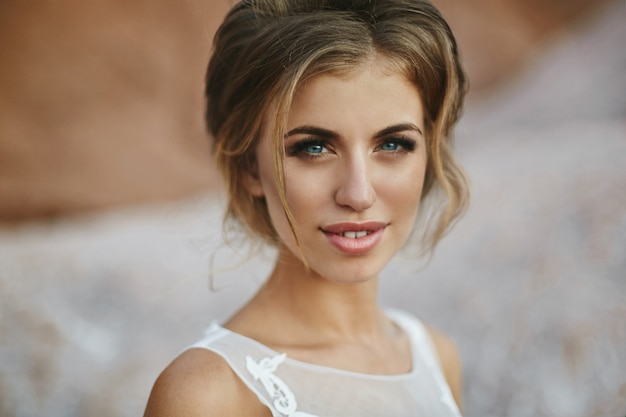Retrato de una bella y sensual chica modelo con maquillaje brillante, labios carnosos y ojos azules, en un elegante vestido de encaje posando al aire libre
