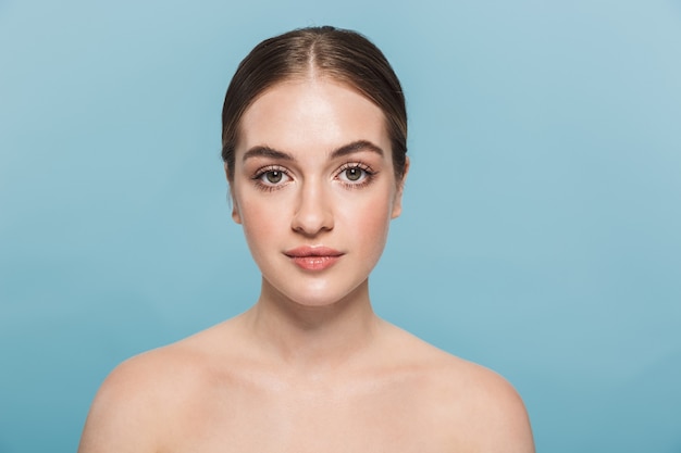 Retrato de belleza de una atractiva joven en topless aislada sobre pared azul, posando