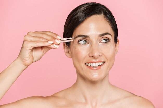 Retrato de belleza de una atractiva mujer morena en topless saludable sonriente aislada, con pinzas