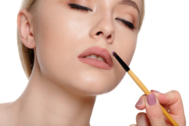 Retrato de belleza de una bella mujer semidesnuda sonriente posando con pinceles de maquillaje