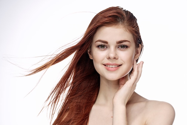 Retrato de la belleza de la cara hermosa de una niña con el pelo rojo volador sobre un fondo blanco