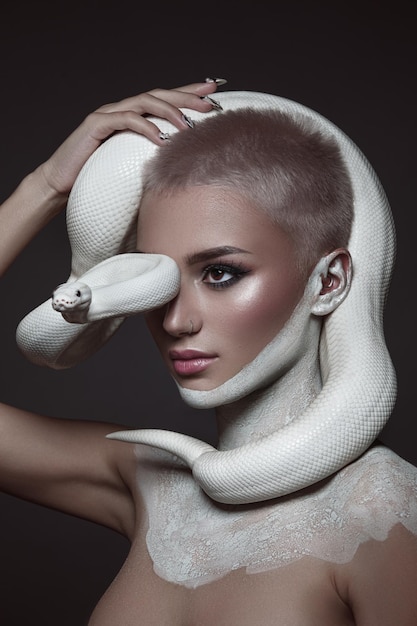 Retrato de belleza creativa de una niña con una serpiente blanca