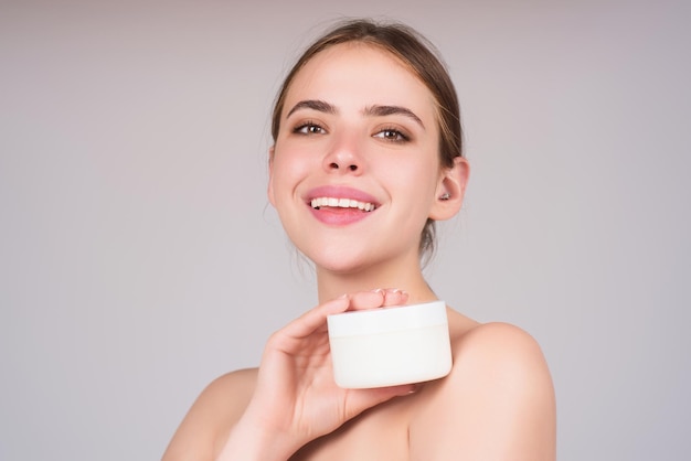 Retrato de belleza para el cuidado de la piel de una mujer hermosa que aplica crema facial aislada en el fondo del estudio