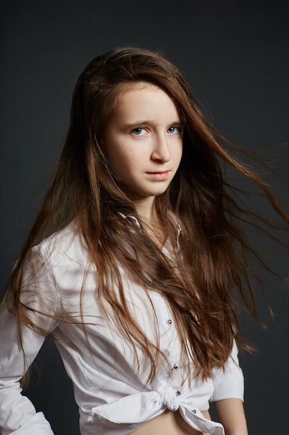 Retrato de la belleza de una hermosa joven en una pared oscura. Cosméticos para adolescentes, tratamiento del acné.