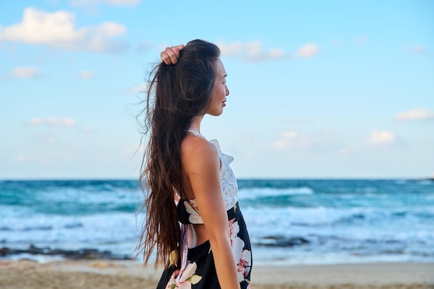 Retrato de belleza de una hermosa joven con el pelo largo en la playa del mar