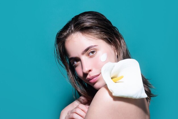 Retrato de belleza de una hermosa mujer medio desnuda aplicando crema facial aislada en el fondo del estudio