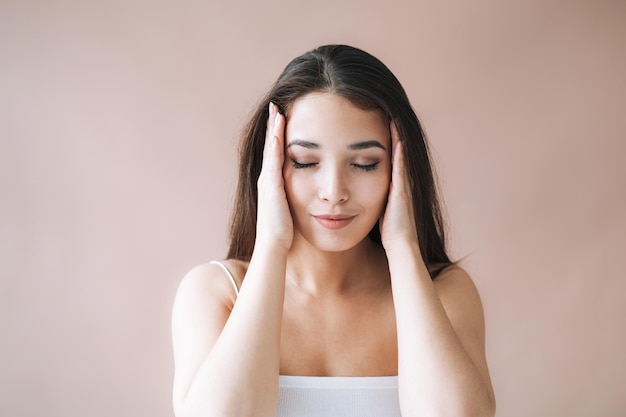 Retrato de belleza de una joven asiática con cabello largo oscuro y saludable en la parte superior sobre fondo beige