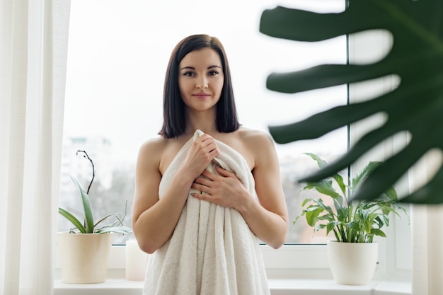 Retrato de la belleza de la joven mujer morena en toalla de baño