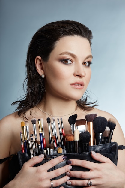 Retrato de belleza de una maquilladora femenina. Pinceles de maquillaje en manos de una niña