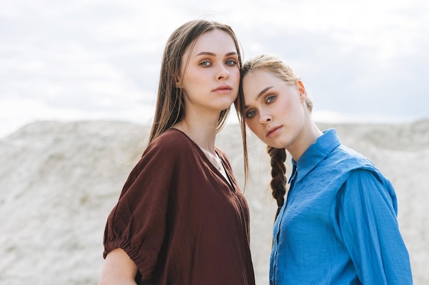 Retrato de belleza de moda de hermanas jóvenes con camisas orgánicas marrones y azules en el fondo del desierto