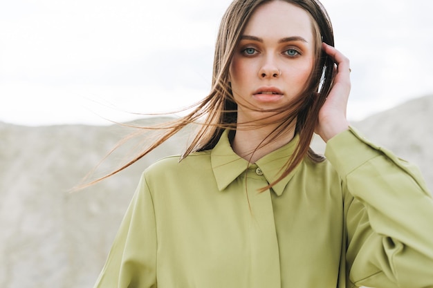 Retrato de belleza de moda de mujer joven con cabello largo en camisa orgánica verde en el fondo del desierto