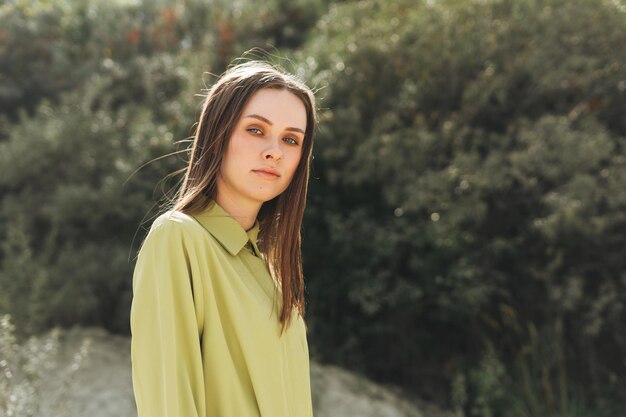 Retrato de belleza de moda de mujer joven con cabello largo en el traje orgánico verde al aire libre