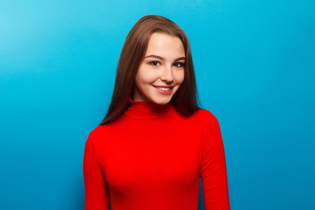 Foto retrato de belleza de moda mujer joven sonriente en fondo azul de la pared