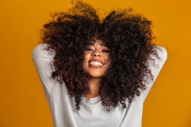 Retrato de belleza de mujer afroamericana con peinado afro y maquillaje glamour. Mujer brasileña Raza mixta. Pelo RIZADO. Peinado. pared amarilla