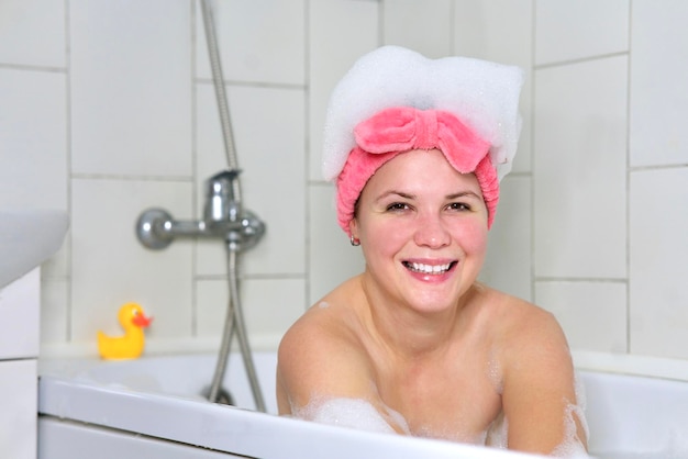 Retrato de la belleza de la mujer alegre joven hermosa feliz positiva chica es relajante acostado en el baño