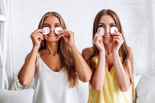 Retrato de belleza de una mujer alegre quitándose el maquillaje de la cara con un algodón