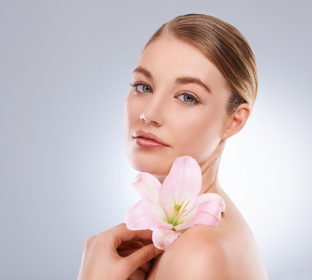 Retrato de belleza y mujer con flores de cuidado de la piel y bienestar en fondo blanco de estudio Cara de persona y modelo con cosméticos naturales y aseo con brillo y brillo con estética o dermatología