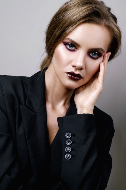 Retrato de belleza de mujer en gris, modelo de moda con piel limpia y hermosos labios, maquillaje de ojos ahumados de color morado oscuro