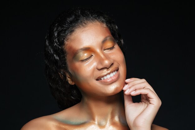 Retrato de belleza de mujer joven americana feliz con maquillaje de moda sobre negro