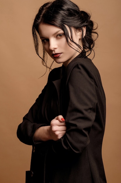 Retrato de la belleza de una mujer joven en una pared de color beige