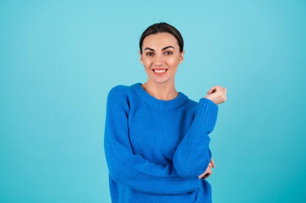 Retrato de belleza mujer joven en un suéter de punto azul y maquillaje de día natural, sonriendo alegremente, sonrisa romántica confiada