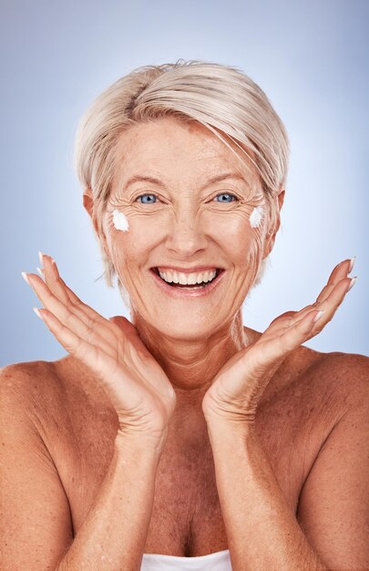 Retrato de belleza de una mujer madura y crema para el cuidado de la piel, antienvejecimiento y bienestar en un fondo de estudio gris Hidratante o loción para el cuidado de la piel con una mujer mayor que aplica crema solar o spf en la cara