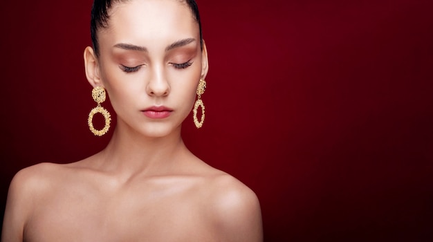 Retrato de belleza de mujer posando con aretes de oro