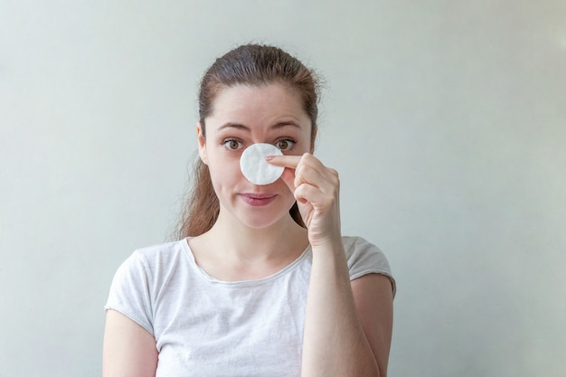 Retrato de belleza mujer quitando el maquillaje con algodón aislado en blanco