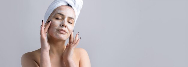 Retrato de belleza de mujer con toalla blanca en la cabeza aplica crema en la cara Cuidado de la piel limpieza eco cosmética orgánica spa relax concepto