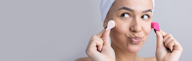 Retrato de belleza de mujer con toalla blanca en la cabeza con una esponja para un cuerpo a la vista de un corazón rosa Cuidado de la piel limpieza eco cosmética orgánica spa relax concepto