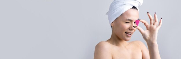 Retrato de belleza de mujer con toalla blanca en la cabeza con una esponja para un cuerpo a la vista de un corazón rosa Cuidado de la piel limpieza eco cosmética orgánica spa relax concepto