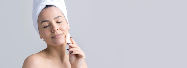 Retrato de belleza de mujer con toalla blanca en la cabeza con una esponja para un cuerpo a la vista de un corazón rosa Cuidado de la piel limpieza eco cosmética orgánica spa relax concepto