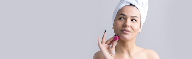 Retrato de belleza de mujer con toalla blanca en la cabeza con una esponja para un cuerpo a la vista de un corazón rosa Cuidado de la piel limpieza eco cosmética orgánica spa relax concepto