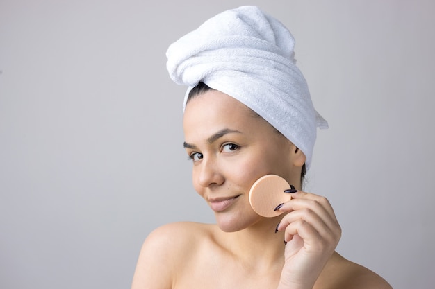 Retrato de belleza de mujer con toalla blanca en la cabeza con una esponja para un cuerpo a la vista de un corazón rosa