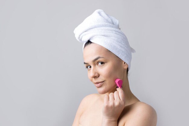 Retrato de belleza de mujer en toalla blanca en la cabeza con una esponja para un cuerpo a la vista de un corazón rosa