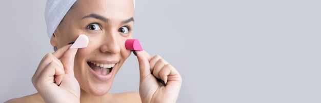 Retrato de belleza de mujer en toalla blanca en la cabeza con una esponja para un cuerpo a la vista de un corazón rosa