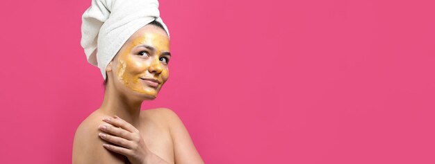 Retrato de belleza de mujer en toalla blanca en la cabeza con máscara nutritiva dorada en la cara Cuidado de la piel limpieza eco cosmética orgánica spa relax concepto