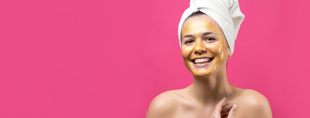 Retrato de belleza de mujer en toalla blanca en la cabeza con máscara nutritiva dorada en la cara Cuidado de la piel limpieza eco cosmética orgánica spa relax concepto