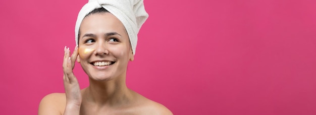 Retrato de belleza de mujer en toalla blanca en la cabeza con máscara nutritiva dorada en la cara Cuidado de la piel limpieza eco cosmética orgánica spa relax concepto