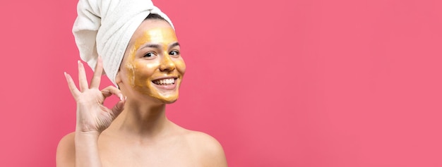 Retrato de belleza de mujer en toalla blanca en la cabeza con máscara nutritiva dorada en la cara