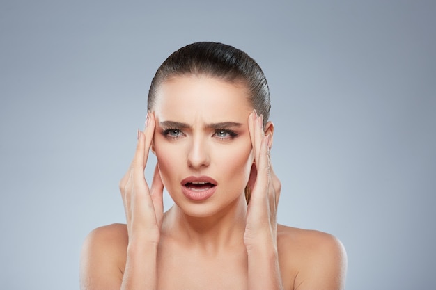 Retrato de belleza de niña cansada mirando a un lado con dolor. Cabeza y hombros de mujer que sufre de dolor de cabeza. Maquillaje natural, estudio, verdaderas emociones