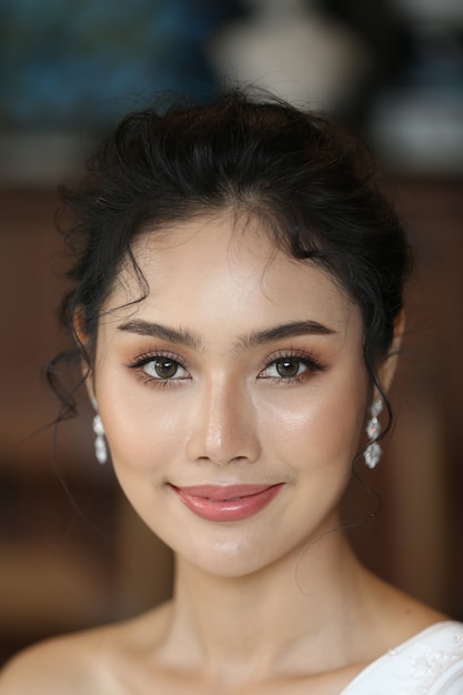 Retrato de belleza de novia con vestido de novia de moda con plumas con maquillaje y peinado de lujo, estudio de fotografía interior. Modelo caucásico asiático multirracial atractivo joven