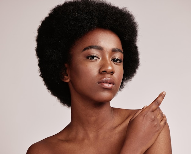 Retrato de belleza o piel y una mujer negra modelo en estudio sobre un fondo gris con cabello afro Cosméticos para el cuidado de la piel y naturales con una atractiva mujer joven posando en el interior para la salud o el bienestar