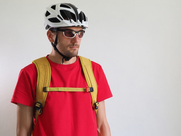 Foto retrato de bicicleta courier, con mochila amarilla. hombre con casco y gafas. fondo blanco.