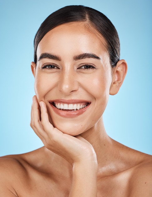 Retrato de bienestar y mujer en un estudio con una rutina de belleza facial y natural para el cuidado de la piel Cuidado personal de la salud y modelo femenino feliz con un tratamiento cosmético para la cara o la piel con un fondo azul