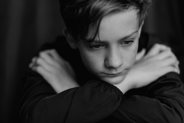 Retrato en blanco y negro de un adolescente sobre fondo oscuro Toma de primer plano de un joven adolescente Fotografía en blanco y negro Enfoque selectivo